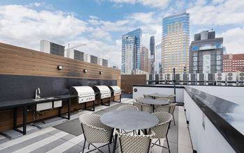 a rooftop patio with tables and chairs and a city skyline